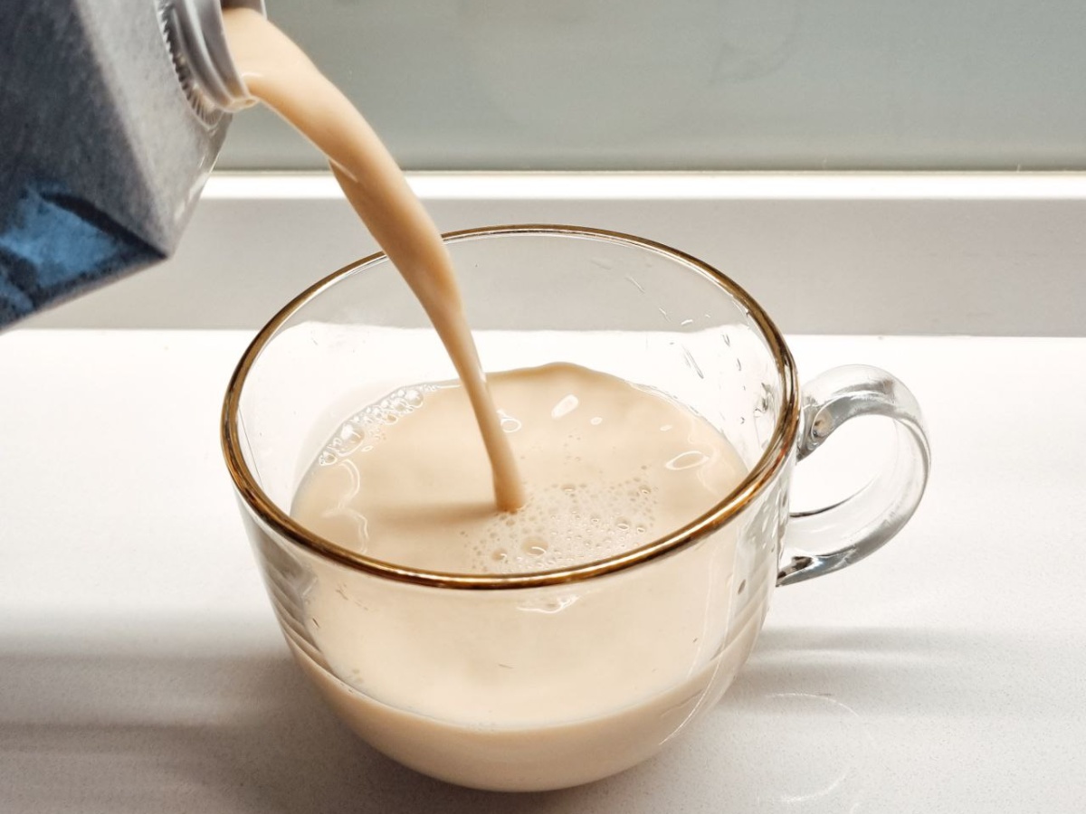 oat milk-pouring oat milk into a cup