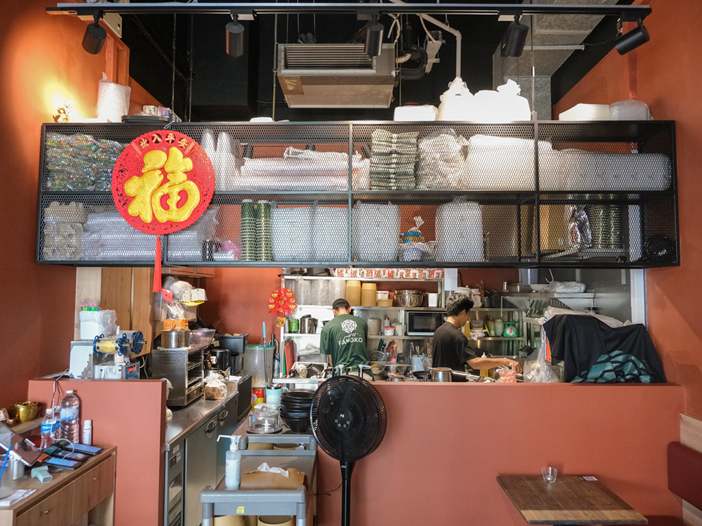 Baby Fangs’s space is functional, with rustic wooden tables, basic chairs, and an open kitchen that consumes a third of the unit. Photo: Gary Lim/HungryGoWhere baby fangs
