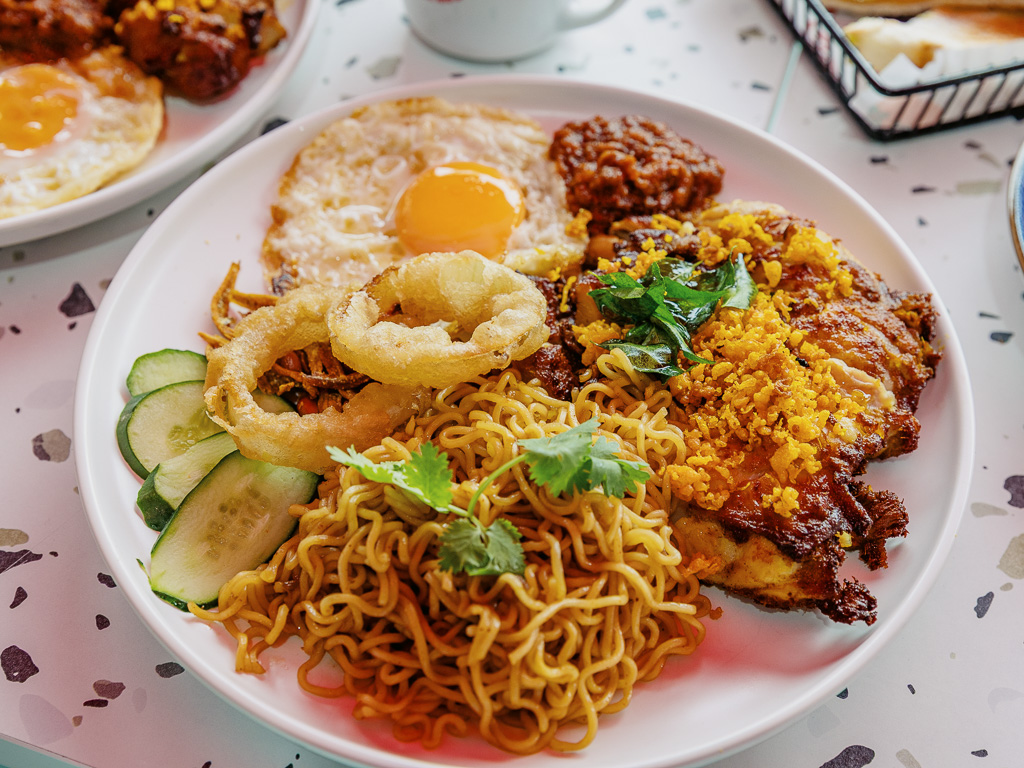 Heartland by Enjoy’s fried chicken berempah with Indomie. Each set includes ikan bilis, roasted peanuts, fried egg, homemade onion rings, cucumber and house sambal. Photo: Ravin Thiruchelvam/HungryGoWhere Heartland by Enjoy