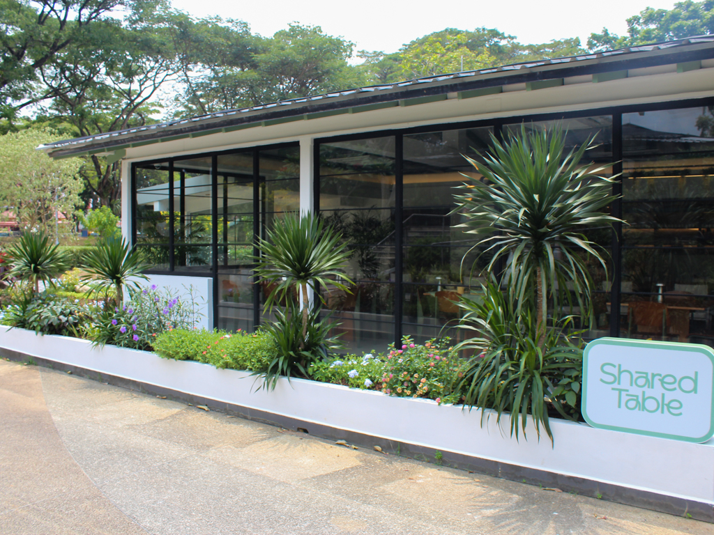 Shared Table's glasshouse storefront, framed by lush greenery and floor-to-ceiling windows. Photo: Angeline Ang/HungryGoWhere shared table bishan ang mo kio park